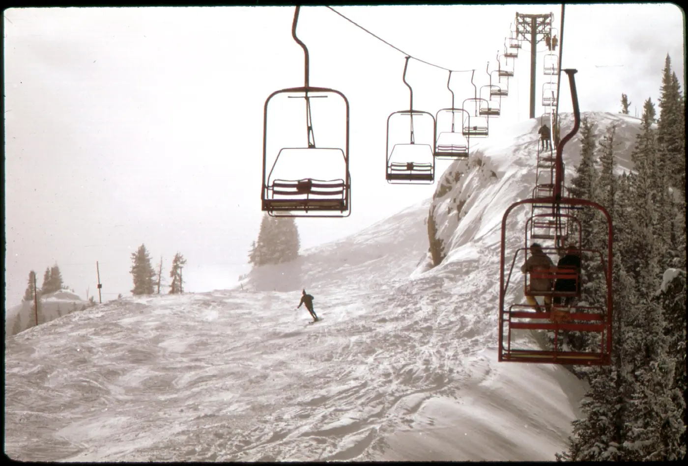 Chairlift ascending Aspen Highlands through fresh snow
